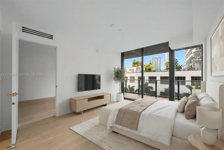 Floor-to-ceiling windows, wood-finish flooring, private balcony with black metal railing, and recessed ceiling lighting - staged
