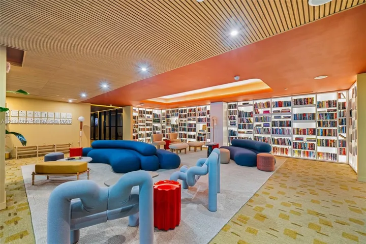 Custom floor-to-ceiling built-in library shelving with integrated LED illumination, wood-slat ceiling detailing, recessed lighting, and patterned carpeting
