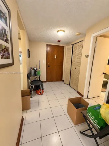 Entryway featuring ceramic tile flooring, solid wood-finish entry door, and bi-fold closet doors with louvered panels