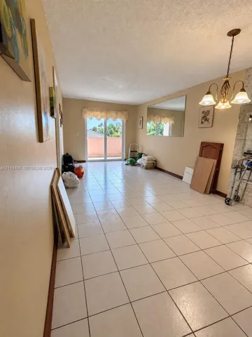 Tile flooring, multi-light hanging chandelier, wall-mounted mirror, and sliding glass door