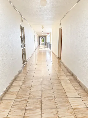 Hallway featuring ceramic tile flooring, textured wall finishes, and flush-mount ceiling lighting