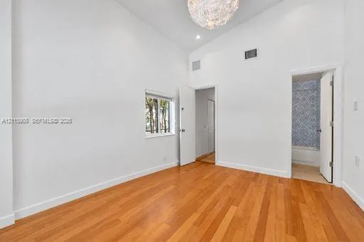 Vaulted ceilings, wood-finish flooring, recessed lighting, and a decorative chandelier