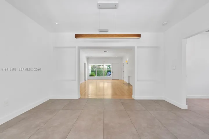 Large-format tile flooring, recessed wall niches, and a linear wood-finish pendant light fixture
