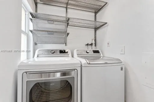 Laundry area featuring wall-mounted wire shelving, two pull-out metal storage baskets, and high-capacity laundry appliances