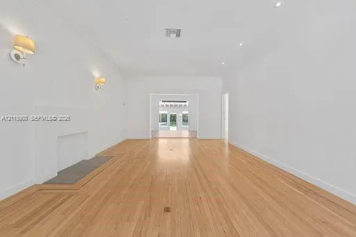 Open-concept interior featuring light wood-finish flooring, a neutral color palette, recessed lighting, wall-mounted light fixtures, and a decorative fireplace.