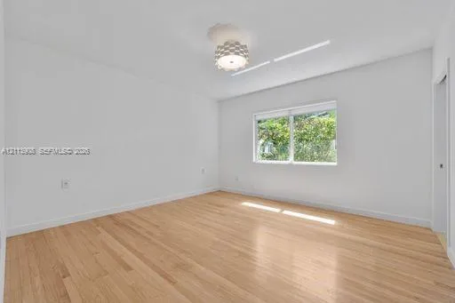 Room featuring wood-finish flooring, a contemporary geometric flush-mount light fixture, and a single-pane window