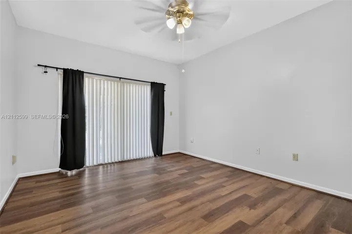 Room featuring wood-finish flooring, sliding glass doors, and a ceiling fan with integrated lighting