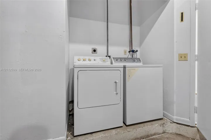 Laundry alcove featuring side-by-side white washer and dryer units with dedicated utility hookups