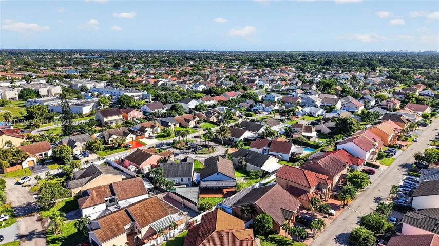 Aerial perspective of a suburban neighborhood featuring paved streets, established residential lots, mature landscaping, and diverse roofline profiles