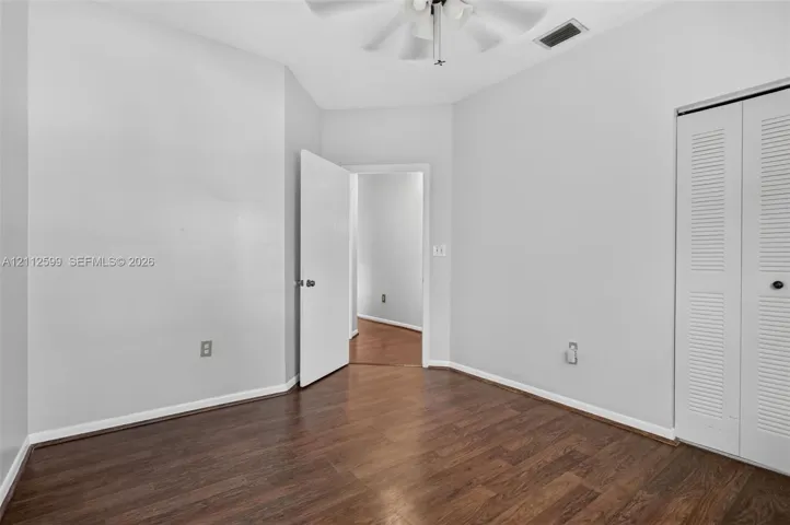 Interior room featuring wood-finish flooring, a ceiling fan with integrated lighting, and a bi-fold louvered closet door