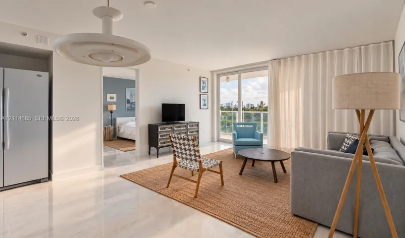 Open-concept living space featuring polished tile flooring, contemporary circular overhead lighting, a floor-to-ceiling sliding glass door, and built-in full-size refrigerator