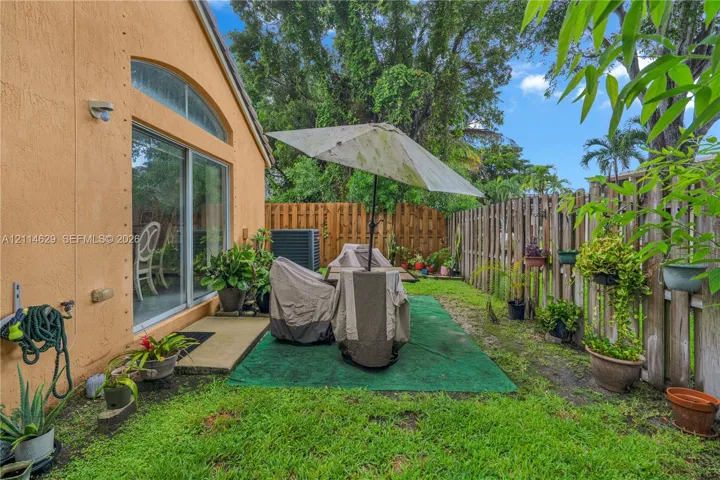 Stucco exterior featuring a sliding glass door with an arched transom window, a fenced backyard, and a concrete patio slab