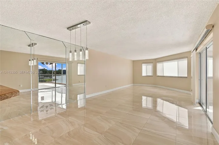 Large-format polished tile flooring, wall-to-wall mirrored accent paneling, multi-pendant linear lighting fixture, and sliding glass doors with window treatments
