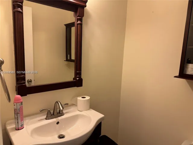 Wall-mounted vanity featuring a porcelain drop-in sink, metallic dual-handle faucet, and decorative dark-finished wood-frame mirror