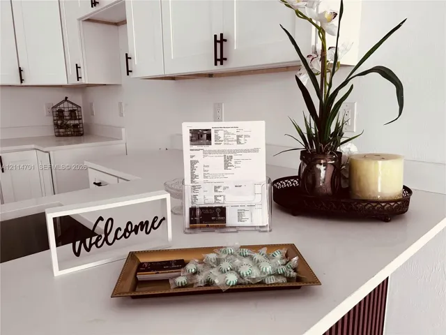 White shaker-style cabinetry with matte black hardware and solid-surface countertops