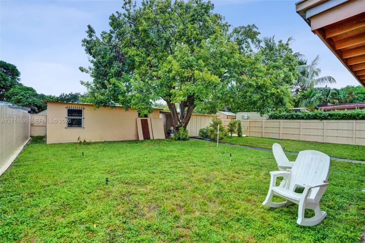 Backyard featuring a grass lawn, mature tree, and perimeter privacy fencing