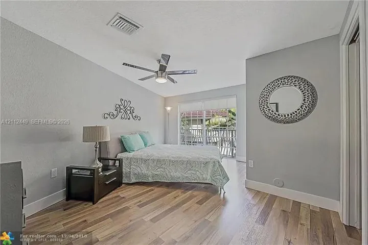 Room featuring wood-finish flooring, a ceiling fan with integrated lighting, and glass sliding doors providing exterior exposure