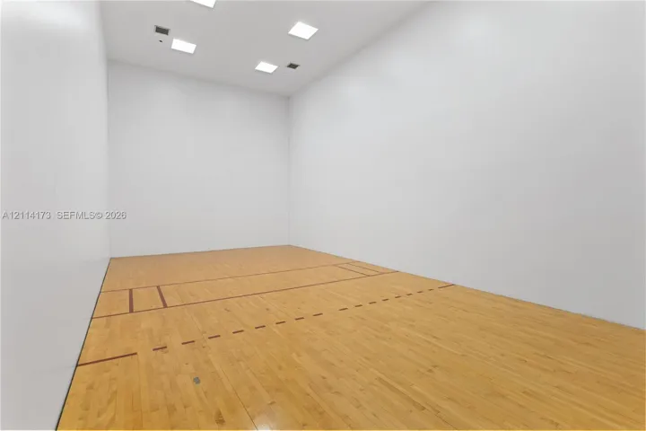 Recreational court featuring smooth panel walls, wood-finish flooring with court markings, and recessed ceiling lighting