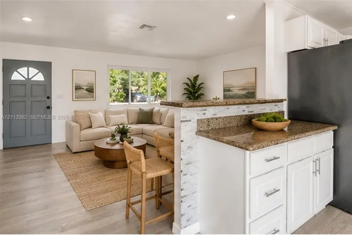 Kitchen featuring white cabinetry, stone-surfaced peninsula with a tiled front, wood-finish flooring, and recessed ceiling lighting