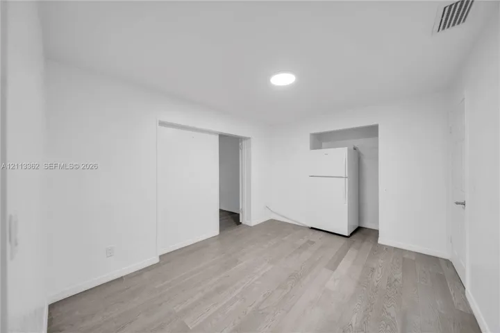 Interior space featuring wood-finish flooring, recessed ceiling lighting, and a white top-mount refrigerator set within a recessed alcove
