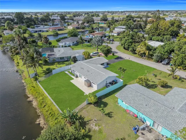 Waterfront property featuring a fenced backyard, paved patio, sprawling lawn, and mature landscaping