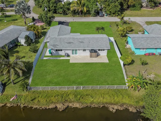 Waterfront property featuring a fenced backyard, paved patio, and grass lawn