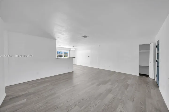 Open-concept living space featuring wood-finish flooring, a built-in partition wall, and a multi-panel door with glass inserts