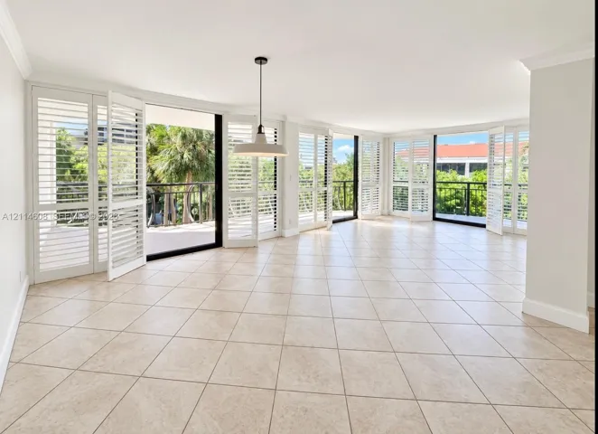 Open floor plan featuring light-toned tile flooring, floor-to-ceiling multi-panel glass doors, plantation shutters