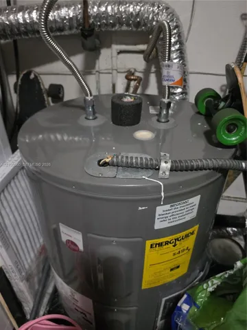 Electric water heater featuring braided metal supply lines, a protective insulation cap, and a metal-clad electrical conduit