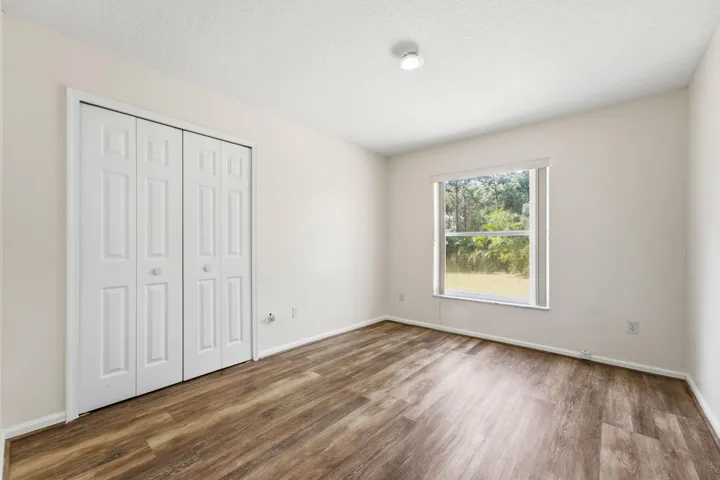 Neutral wall tones, wood-finish flooring, bi-fold closet doors, and a single-pane window
