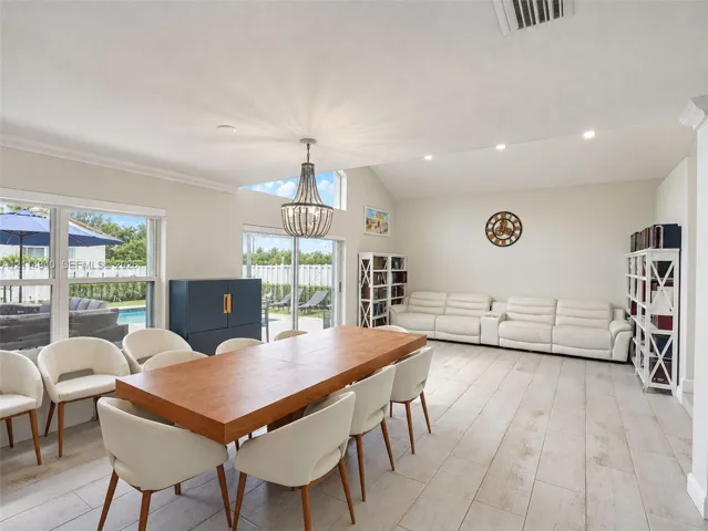 Vaulted ceilings with recessed lighting, wood-finish tile flooring, a statement chandelier, and large sliding glass doors providing natural light