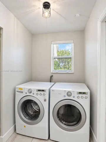 Dedicated laundry space featuring neutral wall paint, a single window, and a geometric-frame ceiling light fixture