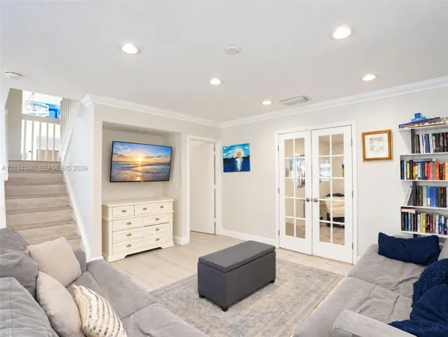 Living area featuring recessed lighting, crown molding, tile flooring, built-in shelving, and double French doors with glass panes