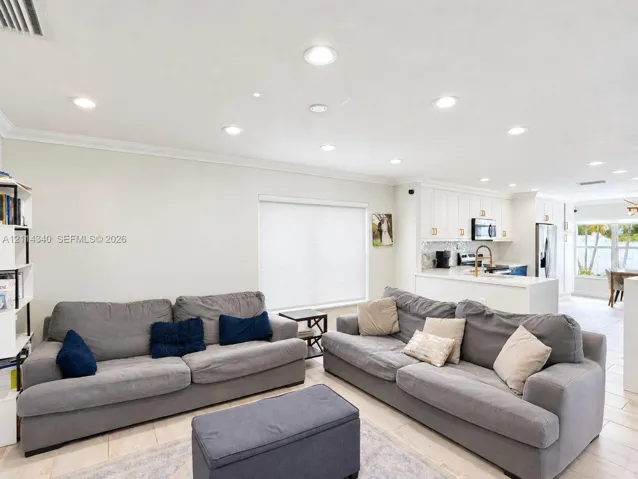 Open-concept interior featuring recessed lighting, crown molding, neutral wall finishes, tile flooring, and white cabinetry