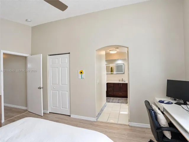High ceilings, arched doorway, wood-finish flooring, and white interior doors