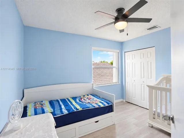 Room featuring wood-finish flooring, a multi-panel bi-fold closet, a ceiling fan with integrated light fixture, and a single-hung window