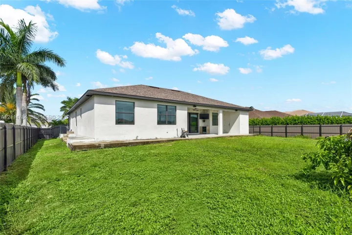 Stucco exterior residence with a covered patio, architectural shingle roof, and full perimeter privacy fencing