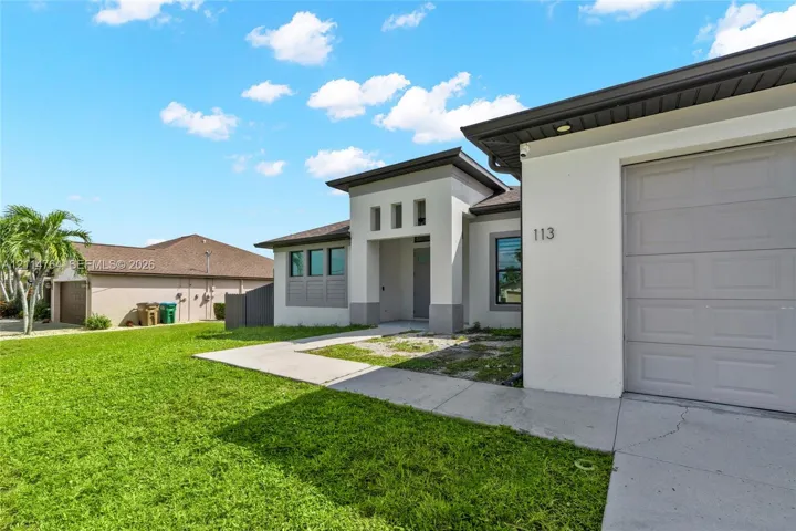 Contemporary stucco exterior featuring a recessed entryway, a multi-panel garage door, and geometric window groupings