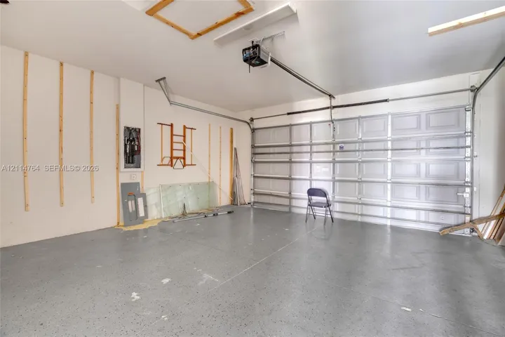 Attached garage featuring epoxy-finished concrete flooring, a sectional overhead door, and a ceiling-mounted automatic door opener