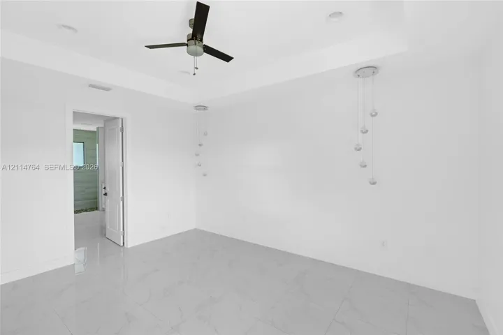 Tray ceiling with recessed lighting, three-blade ceiling fan, and pendant lighting fixtures, finished with large-format stone-look tile flooring