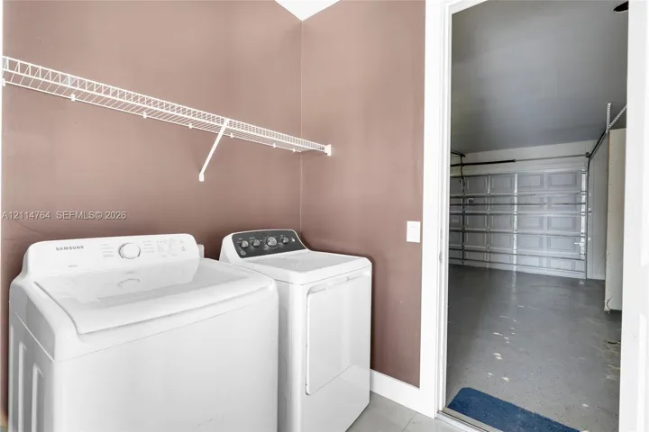 Laundry area featuring wall-mounted wire shelving and a paneled garage door