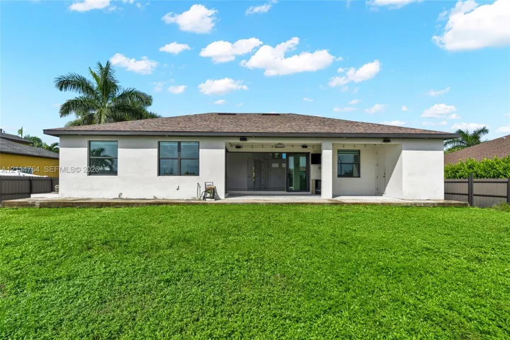 Rear exterior featuring a stucco facade, hipped roof, covered concrete patio, and fenced backyard