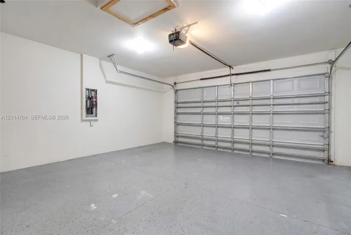 Two-car garage featuring a painted concrete floor, recessed ceiling access, overhead automatic door opener, and interior electrical panel