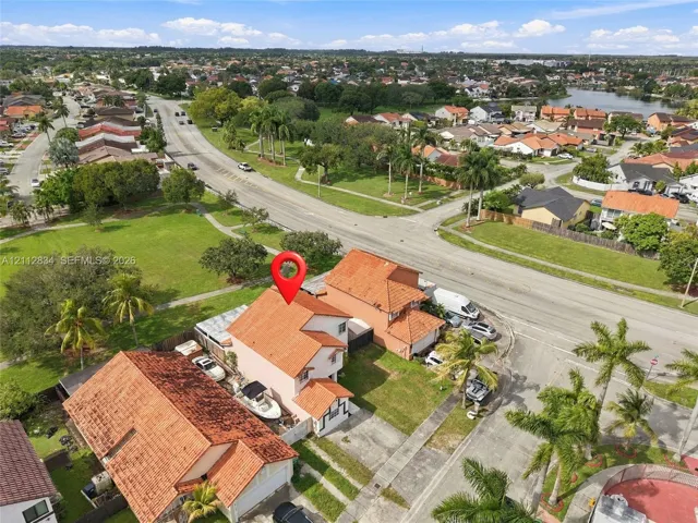 Two-story residence featuring a terracotta tile roof, stucco exterior, paved driveway, and established landscaping