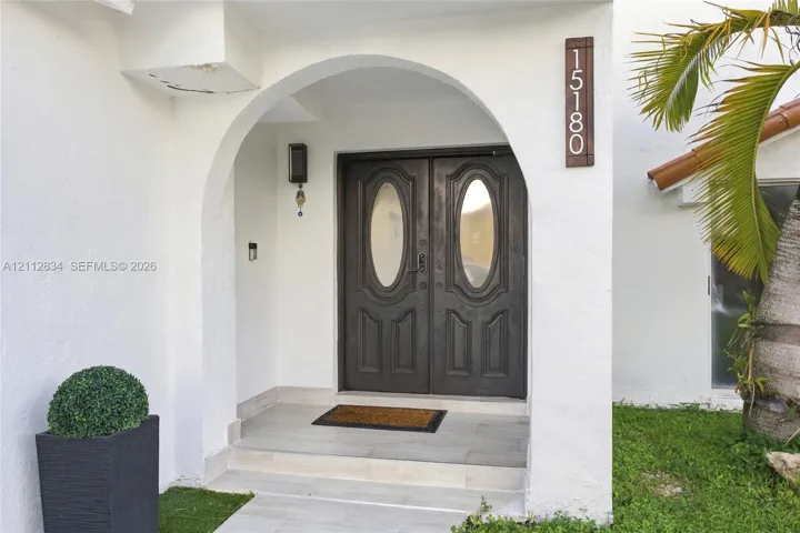 Covered entryway featuring a stucco archway, double doors with glass inserts, and light-toned tile flooring