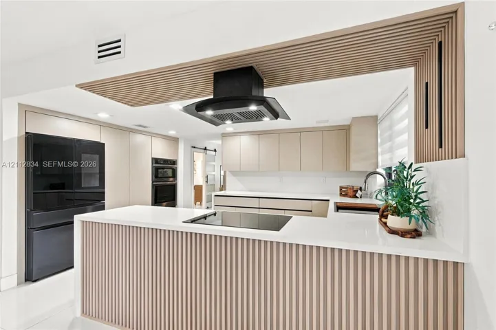 Kitchen featuring flat-panel cabinetry, light-toned vertical wood slat detailing, quartz countertops, a glass cooktop, and a matte black ceiling-mounted range hood