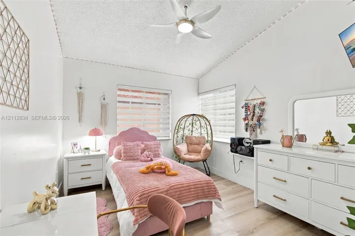 Vaulted ceiling with a central multi-blade ceiling fan and wood-finish flooring throughout