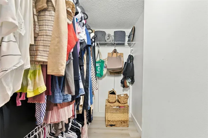 Walk-in closet featuring wire shelving, integrated wall-mounted tracks, and wood-finish flooring