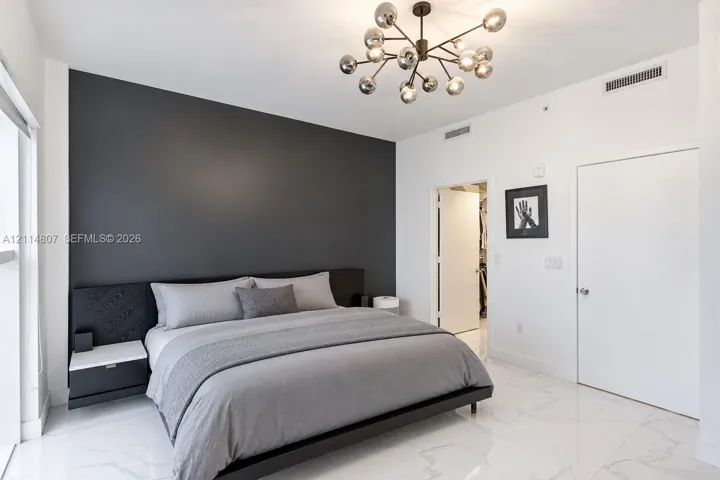 Contemporary interior featuring a charcoal accent wall, white stone-finish flooring, and an adjustable multi-arm light fixture with glass globe shades