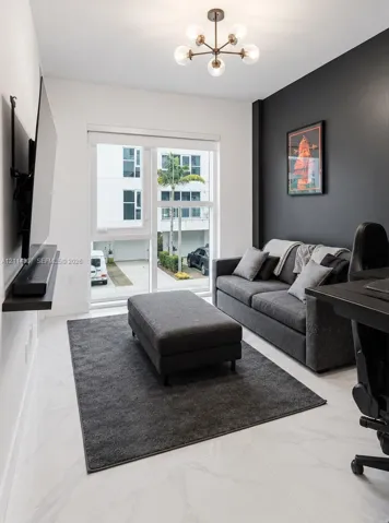 Room featuring white stone-finish flooring, a charcoal accent wall, floor-to-ceiling glass door, and a six-light sputnik-style ceiling fixture